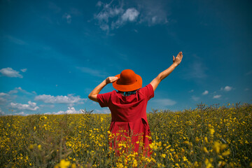 Trendy woman with stylish hat feeling free in the field with flowers