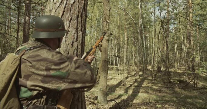 Reenactor Dressed As German Infantry Soldier Shoots From Rifle Carabine Mauser 98k. Weapon Jammed. War Ambush In Forest. Wermacht Military Uniform. Reload And Shooting From Rifle. Reenactment Combat