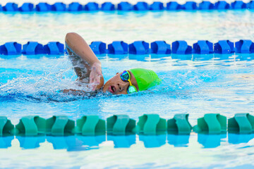 Swimmer child swims freestyle swimming style in a race swimming pool. Water sports and competition,...