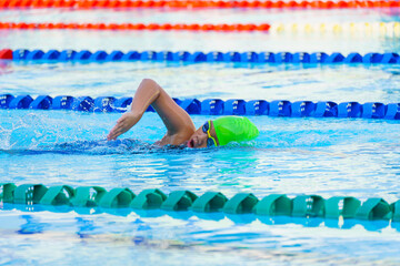 Swimmer child swims freestyle swimming style in a race swimming pool. Water sports and competition,...