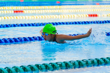 Swimmer child swims butterfly swimming style in a race swimming pool. Water sports and competition,...