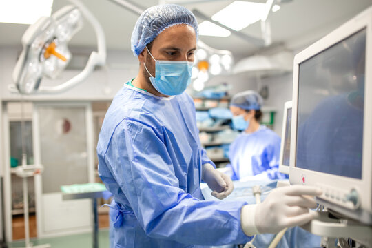Anesthesiologist monitoring patient vital parameters on a digital screen during surgery. Focused doctor adjusting settings on anesthesia equipment to maintain patient stability in the operating room
