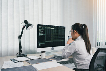Asian female software developer is worried about analyzing code-based systems at his office.