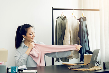 Young asian entrepreneurs are picking up shirts to compare proportions for customers to view them online.