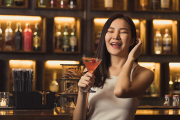 Asian women drinking cocktails and having fun at the bar at night.