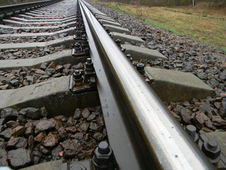 Railway concept. Metal iron sleeper of the railway after rain.