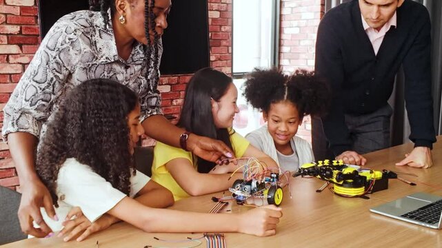 Diverse group of kids learning robotics and coding with teacher guidance in a classroom, building and programming robot toys, promoting STEM education and hands-on tech skills in school projects.
