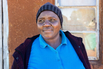 Africa village, single african woman , standing in front of the house in the yard, overweight...