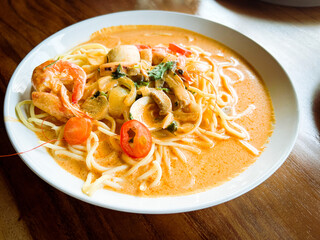 Delicious Bowl Of Creamy Seafood Noodles Garnished With Fresh Herbs And Vegetables