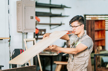 Male carpenter working in the workshop. Portrait of a young carpenter edging wood.