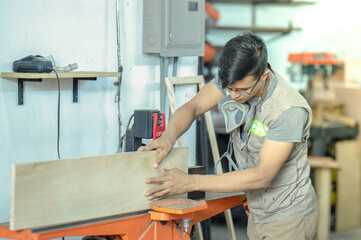 Young carpenter edging wood in his workshop