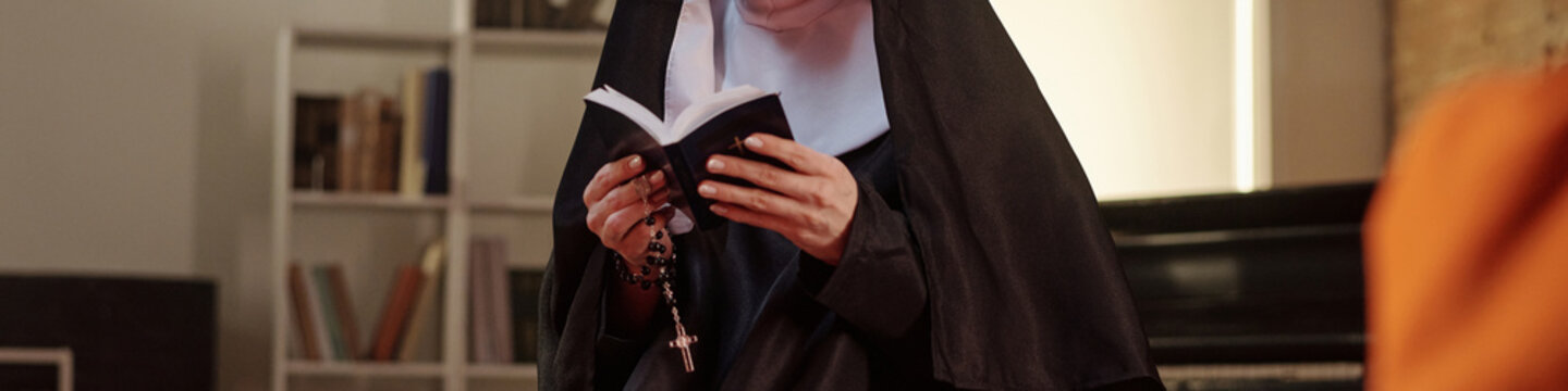 Caucasian nun standing in prison library reading book and holding rosary beads, bookshelves visible in background, engaging in religious or educational activity