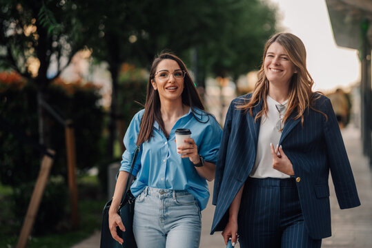 Two businesswomen walking and talking on city street