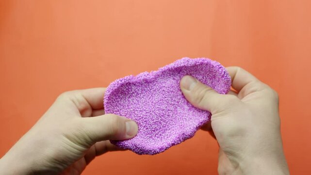 Close-up of pink Floam slime being pulled and stretched in front of a vibrant red backdrop.