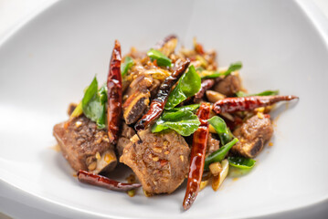 Close-up of a plate of stir-fried meat with red chilies and herbs.