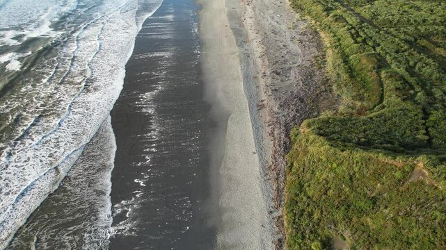 Waves Rolling In Slow Motion Onto Sandy Beach Of Rapahoe With Dense Green Vegetation. Davy Creek Mouth Revealed. aerial tilt-up shot