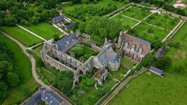 Circular aerial shot of Beauport Abbey in Paimpol showing gardens, vegetation, and surrounding landscape - France