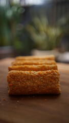 Jakarta, 30 June 2025 : Frozen breaded spring rolls with kaffir lime leaves on wooden background....