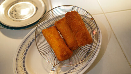 Jakarta, 30 June 2025 : Frozen breaded spring rolls with kaffir lime leaves on wooden background....