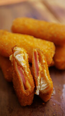 Jakarta, 30 June 2025 : Frozen breaded spring rolls with kaffir lime leaves on wooden background. Raw snack food ready to cook