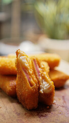 Jakarta, 30 June 2025 : Frozen breaded spring rolls with kaffir lime leaves on wooden background. Raw snack food ready to cook