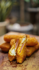 Jakarta, 30 June 2025 : Frozen breaded spring rolls with kaffir lime leaves on wooden background....