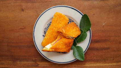 Jakarta, 30 June 2025 : Frozen breaded spring rolls with kaffir lime leaves on wooden background. Raw snack food ready to cook