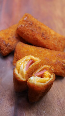 Jakarta, 30 June 2025 : Frozen breaded spring rolls with kaffir lime leaves on wooden background. Raw snack food ready to cook