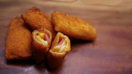 Jakarta, 30 June 2025 : Frozen breaded spring rolls with kaffir lime leaves on wooden background. Raw snack food ready to cook