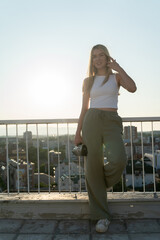 Portrait of a young female filmmaker holding a vintage 8mm video camera on a building rooftop in the golden hour