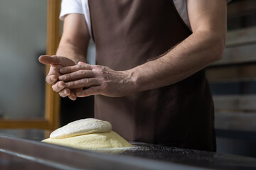 Close up of mans hands kneading dough for preparing pizza