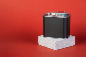 Black can for packaging with stylish props on red background.