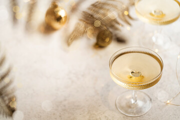 Two champagne glasses on gold shiny background with glitters and balls, top view