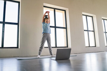 Young child participates in a virtual workout session at home, focusing on fitness and movement