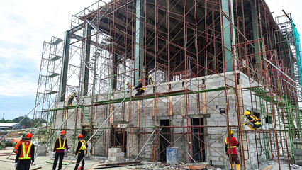 The construction workers working at height at the construction site. Using scaffolding as temporary platform to work. Selective focus. 