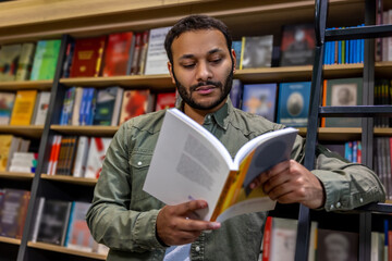 Young bearded dark-haired man reading a book