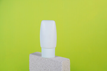 Plastic white tube for cream or lotion. Skin care or sunscreen cosmetic with stylish props on green...
