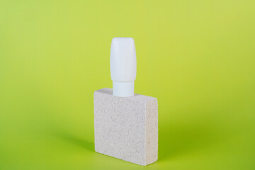 Plastic white tube for cream or lotion. Skin care or sunscreen cosmetic with stylish props on green...