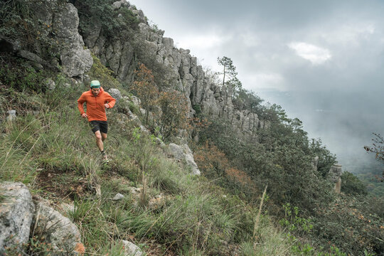 One man trail running on a high hill during a foggy day