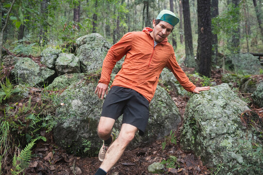 One man running down a trail on a forest beteween big rocks