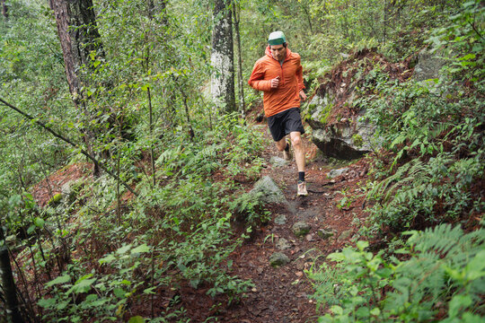 One man running fast on a trail at a green forest