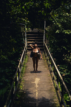 Woman looking up on a bridge in a lush jungle setting