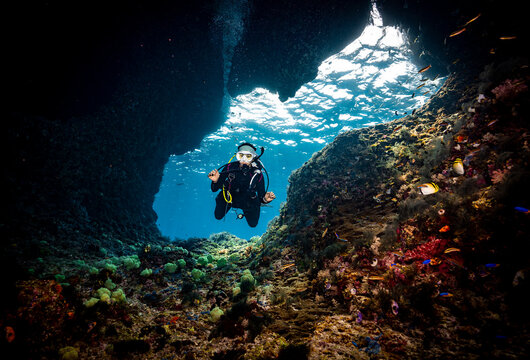 Diver going through swim through at the tropical water of Raja Ampat