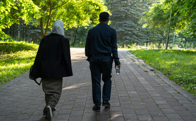 Couple walking together on a sunny path surrounded by greenery in a park during the afternoon