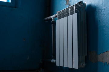 White radiator mounted on blue wall in a dimly lit corner of a room