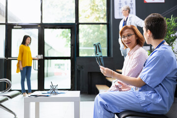 In a hospital lobby, healthcare nurse provides guidance by reviewing X ray scan results. Having a...