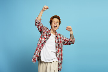 Happy joyful screaming young woman posing clenching fists doing winner gesture