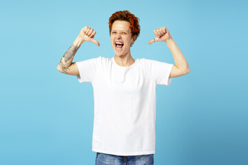 Portrait of emotional queer person in white t shirt standing and screaming, showing thumbs down