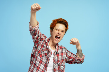 Young woman with positive expression, joyful and exciting, in casual cloth over blue background