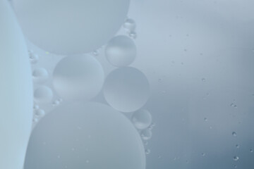 A macro abstract of oil bubbles dispersed in clear liquid, capturing the texture of facial serum....